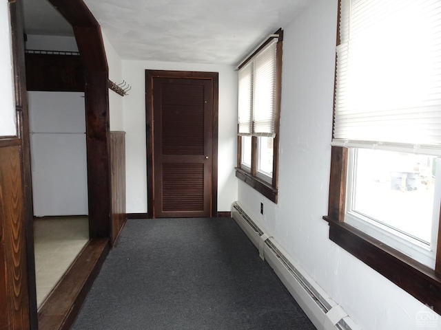 corridor with dark colored carpet and baseboard heating