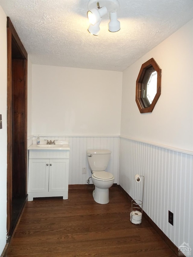 bathroom featuring vanity, a textured ceiling, hardwood / wood-style flooring, and toilet