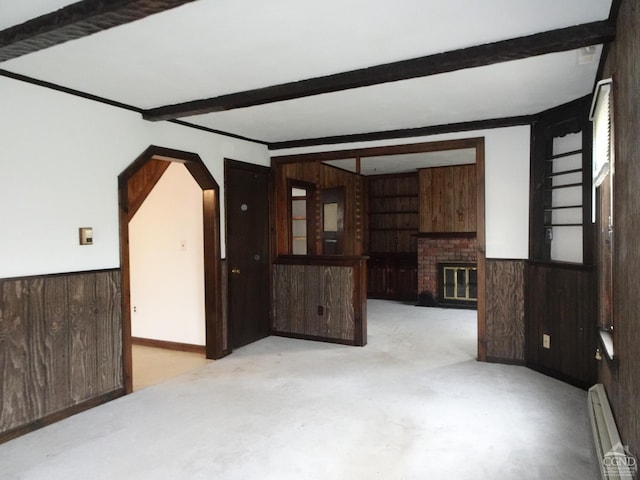 unfurnished room with beamed ceiling, a fireplace, wooden walls, and a baseboard radiator