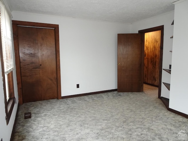 unfurnished bedroom with light carpet, a textured ceiling, and a closet