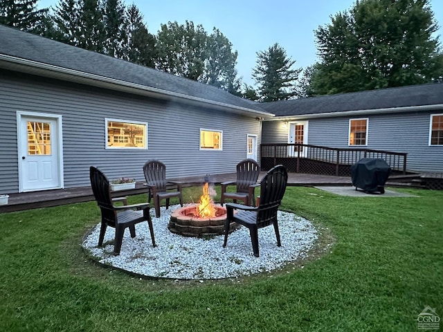 back of property featuring a lawn, a wooden deck, and a fire pit