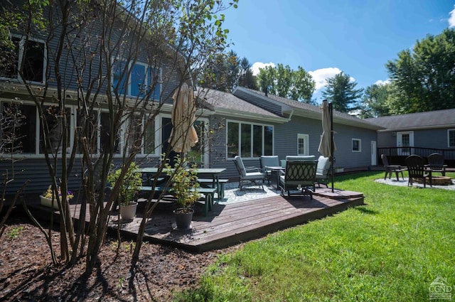 rear view of property featuring a lawn and a deck