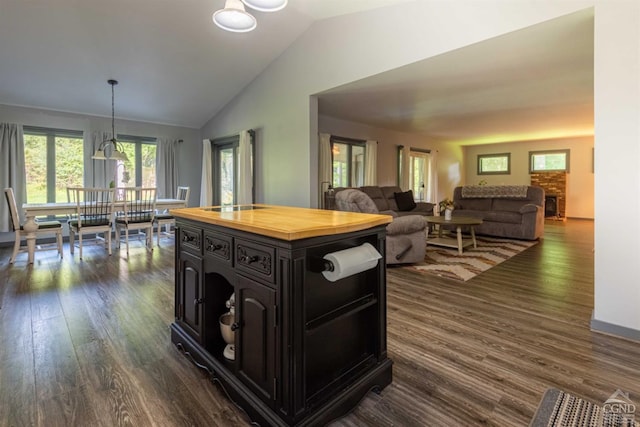 kitchen with dark wood-type flooring, vaulted ceiling, and decorative light fixtures