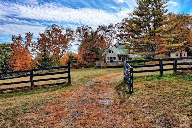 view of gate featuring a rural view, a wooden deck, and a lawn