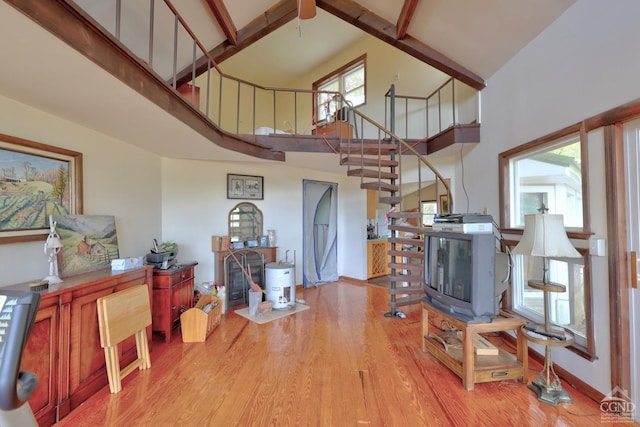 living room with beamed ceiling, light hardwood / wood-style floors, and high vaulted ceiling