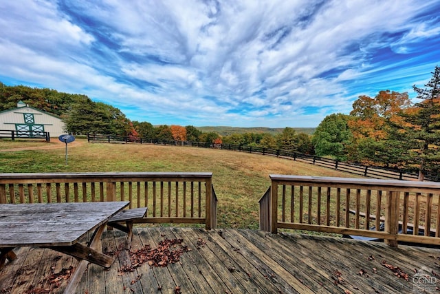 wooden deck with a rural view, an outdoor structure, and a yard