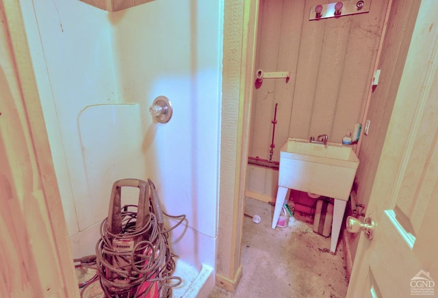 bathroom with a shower, concrete flooring, and sink