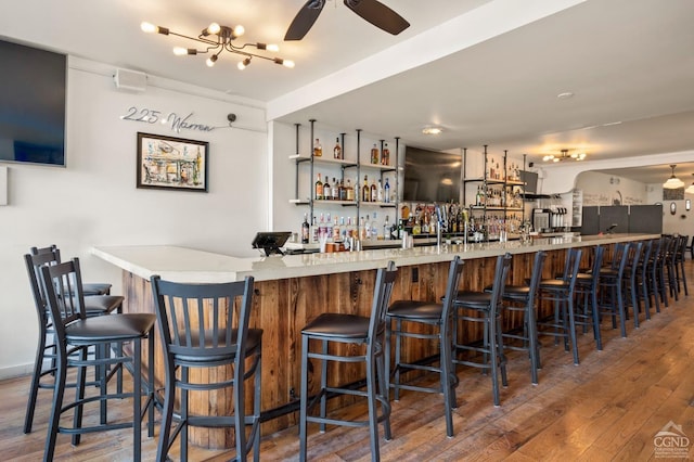 bar with ceiling fan with notable chandelier and dark hardwood / wood-style floors