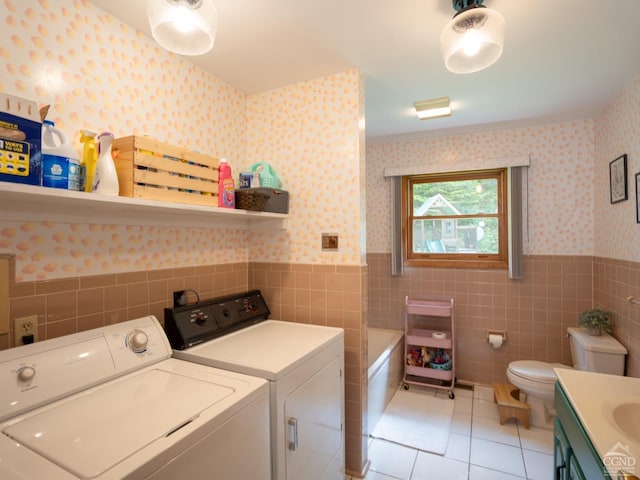 laundry area featuring washing machine and dryer, light tile patterned flooring, and tile walls