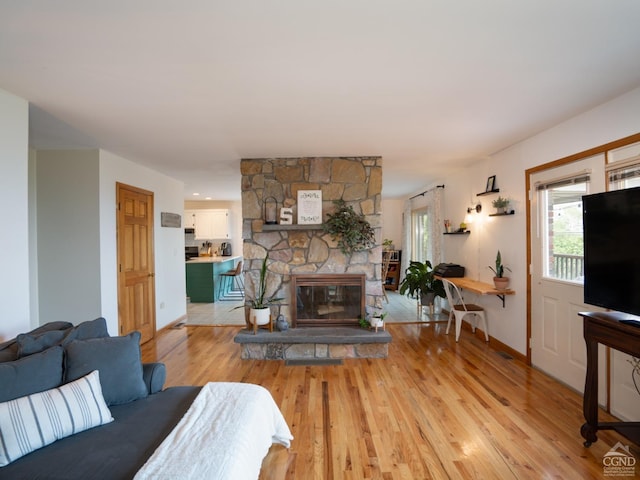 living room with light hardwood / wood-style floors and a stone fireplace