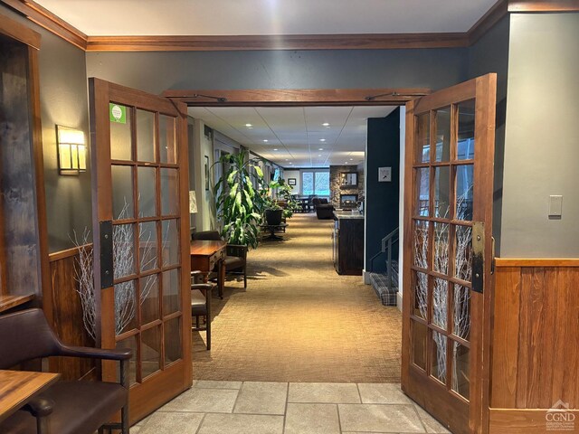 hallway featuring light carpet, crown molding, and french doors