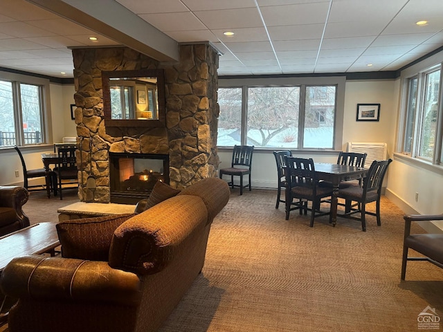 dining area with a stone fireplace, a healthy amount of sunlight, and a drop ceiling