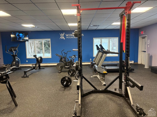 exercise room with a drop ceiling and a wealth of natural light