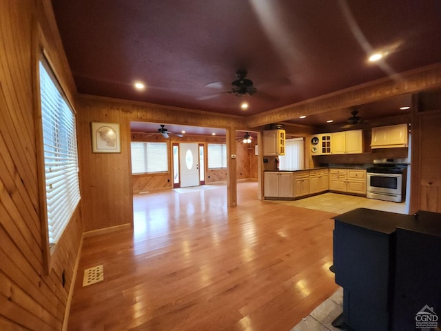 kitchen featuring ceiling fan, stainless steel range, wood walls, and light wood-type flooring