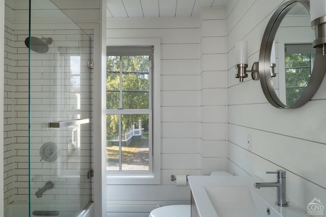 full bathroom with a healthy amount of sunlight, tiled shower / bath combo, toilet, and wooden walls