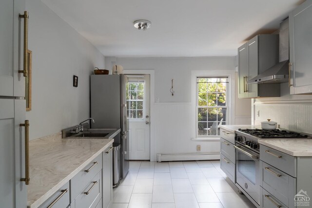 kitchen featuring wall chimney range hood, sink, gray cabinets, baseboard heating, and stainless steel range