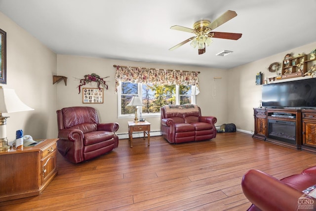 living room with hardwood / wood-style floors, a baseboard radiator, and ceiling fan