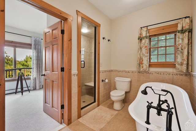 bathroom featuring shower with separate bathtub, a baseboard heating unit, tile walls, and a healthy amount of sunlight