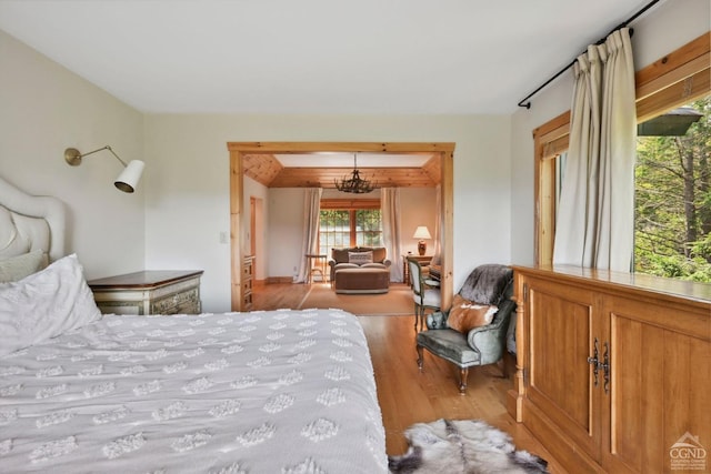 bedroom featuring a chandelier, beam ceiling, and light hardwood / wood-style floors