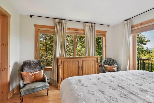 bedroom with access to exterior, light hardwood / wood-style flooring, and multiple windows