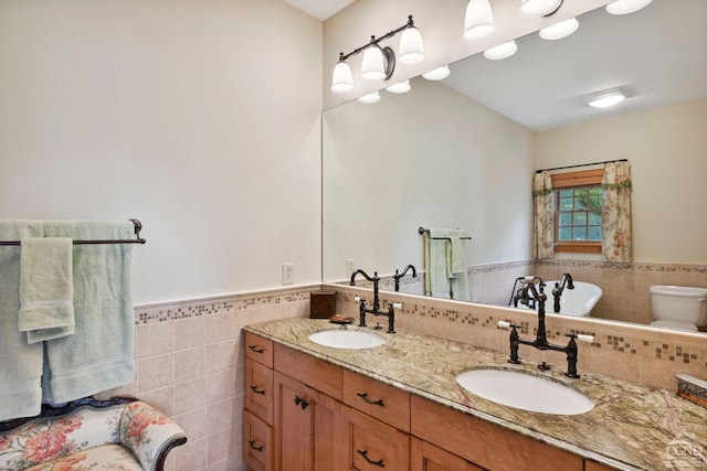 bathroom with vanity, toilet, and tile walls