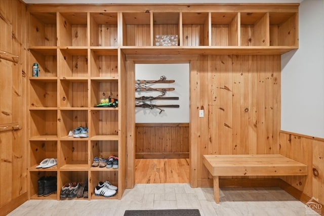 mudroom with hardwood / wood-style floors and wooden walls