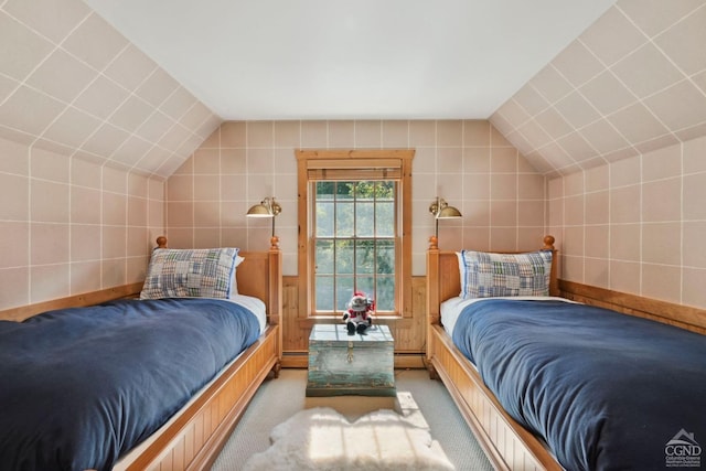 bedroom featuring light colored carpet, tile walls, and vaulted ceiling