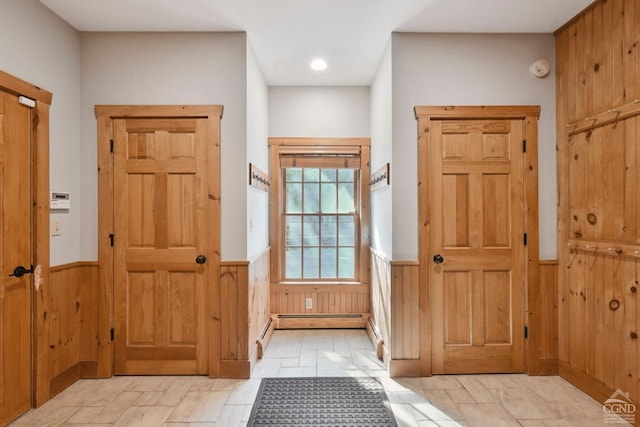 entrance foyer featuring baseboard heating and wooden walls