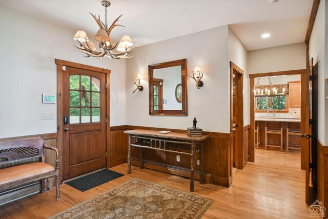 entrance foyer with a chandelier, light hardwood / wood-style floors, and wood walls