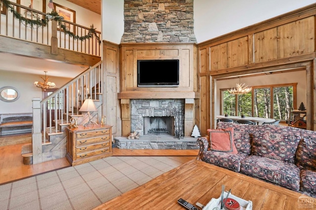 living room with light hardwood / wood-style floors, a stone fireplace, and a towering ceiling