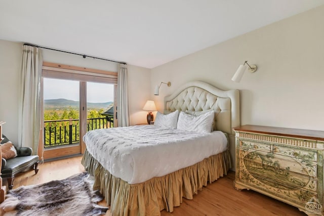 bedroom with a mountain view, wood-type flooring, and access to outside