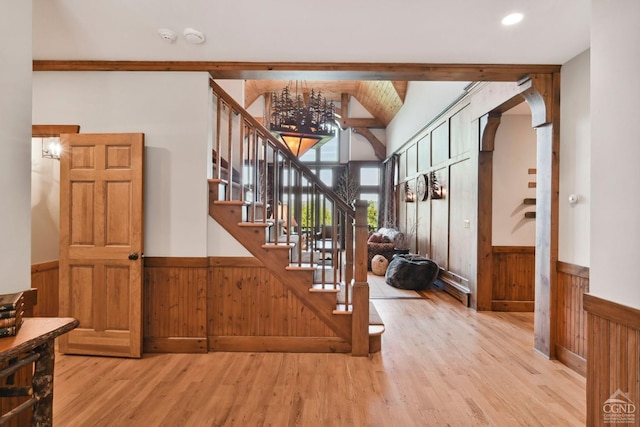 staircase featuring beam ceiling, hardwood / wood-style flooring, and wood walls