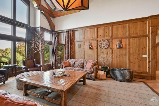 interior space featuring wooden walls, high vaulted ceiling, and light hardwood / wood-style flooring