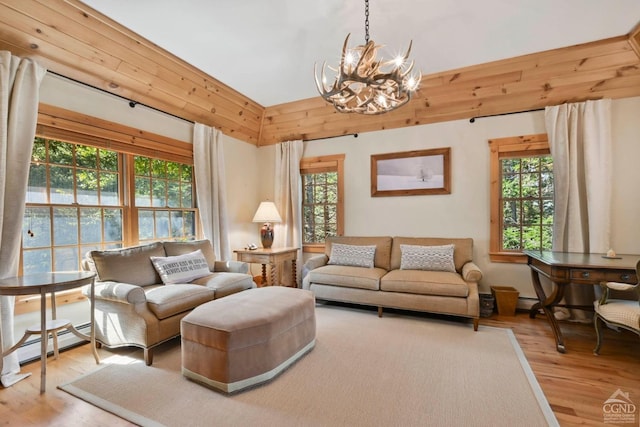 living room with a wealth of natural light, light hardwood / wood-style flooring, a baseboard radiator, and an inviting chandelier