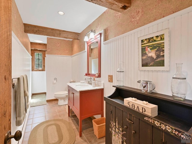 bathroom featuring toilet, vanity, beam ceiling, and tile patterned flooring