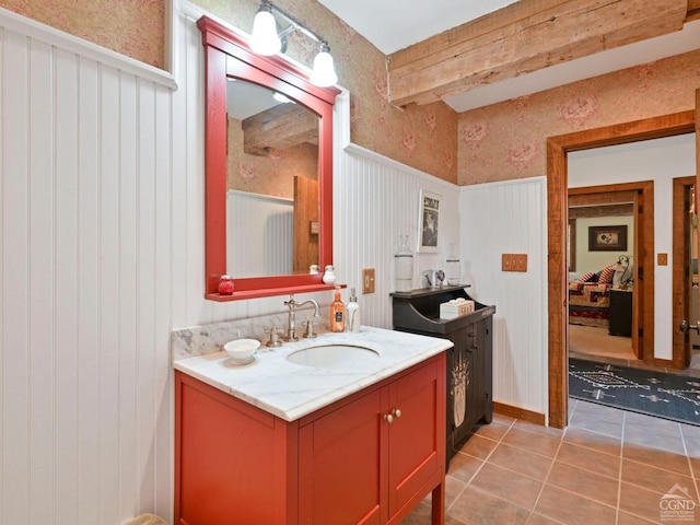 bathroom with beamed ceiling, vanity, and tile patterned flooring