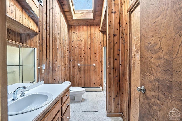bathroom with a skylight, vanity, toilet, and wood walls