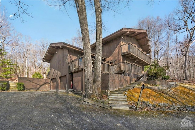 view of side of home with a garage, stairs, and a balcony