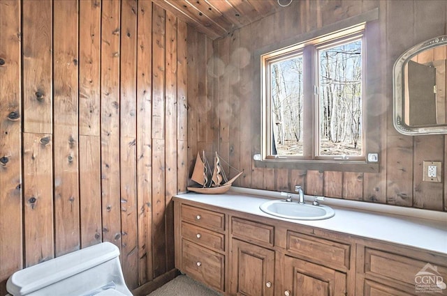 bathroom with toilet, wood walls, wood ceiling, and vanity
