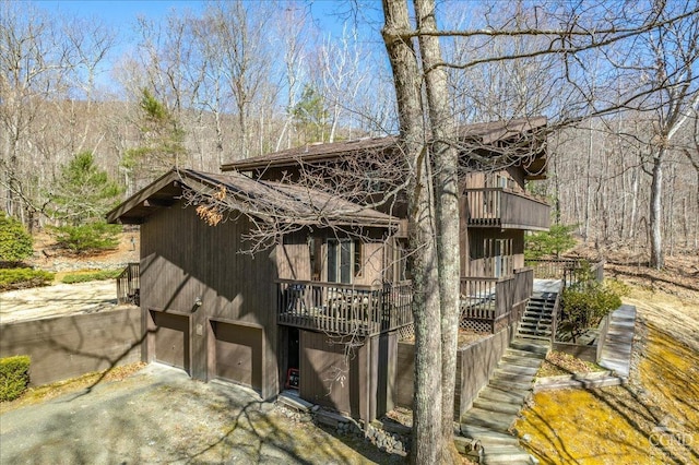 exterior space with stairway, an attached garage, and aphalt driveway