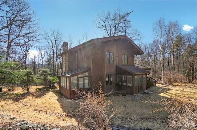 view of home's exterior with a sunroom and a chimney
