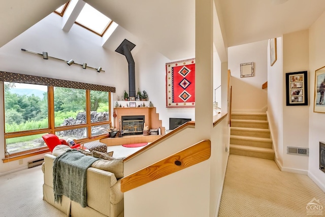 carpeted living room featuring a high ceiling, a skylight, and a baseboard radiator