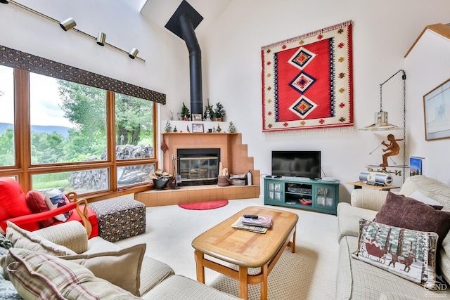 living room with a tile fireplace, carpet floors, and high vaulted ceiling