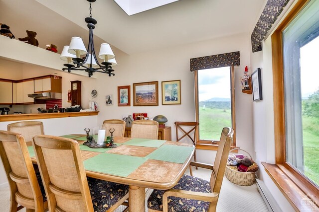 dining room with carpet floors, a healthy amount of sunlight, and a notable chandelier