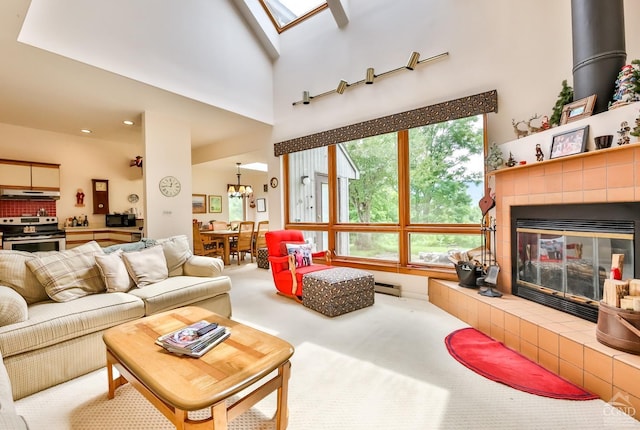 living room featuring a skylight, a high ceiling, a baseboard heating unit, carpet floors, and a fireplace