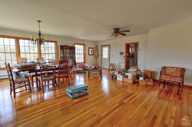 dining area with light wood-style floors and ceiling fan with notable chandelier