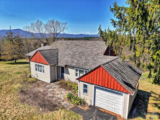 view of side of home with a shingled roof, a mountain view, board and batten siding, and a chimney