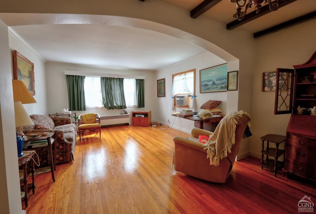 living area featuring crown molding, radiator, cooling unit, arched walkways, and light wood-style flooring