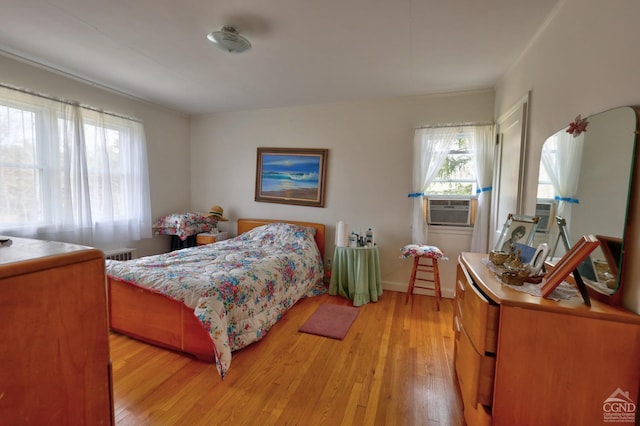 bedroom with baseboards, light wood-style flooring, and cooling unit