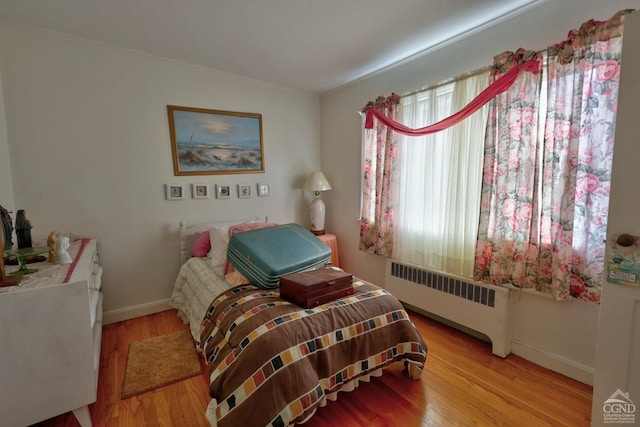 bedroom with baseboards, radiator, and wood finished floors